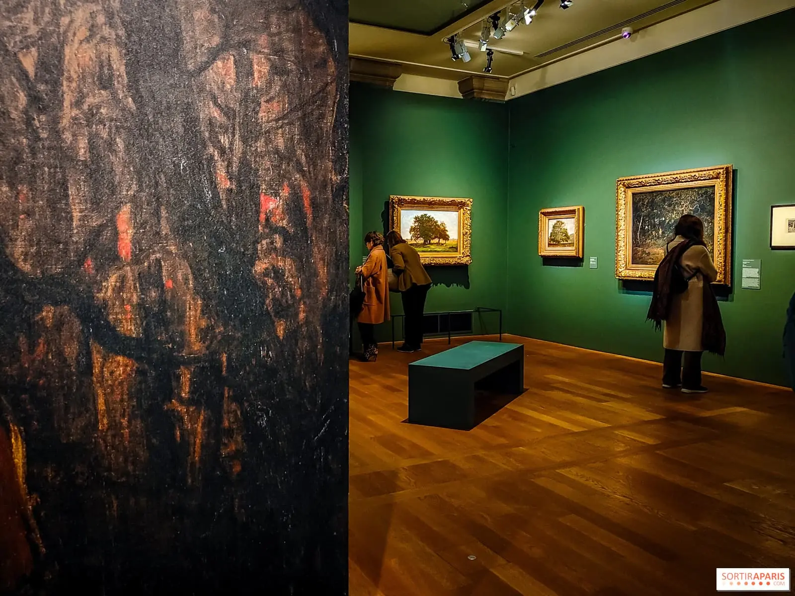 Salle de musée avec des tableaux accrochés aux murs et des visiteurs présents.
